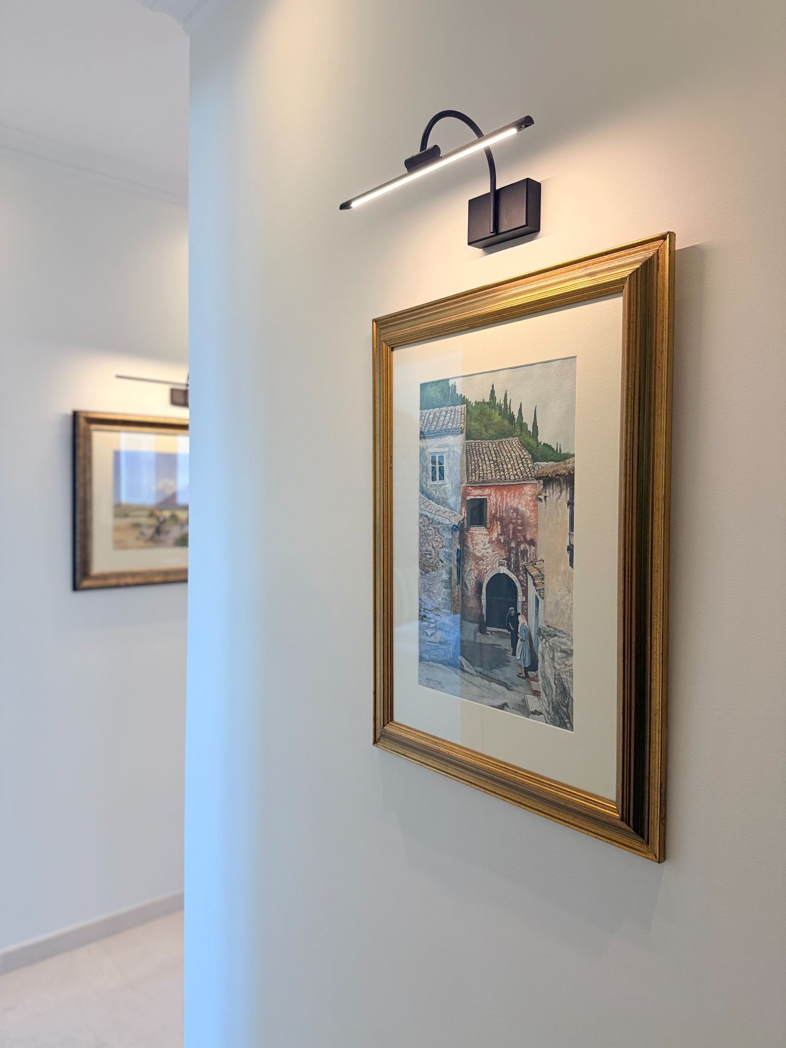 Hallway with framed Corfu watercolours under picture lights
